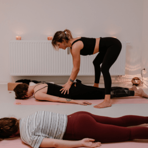 Yogatherapie: Frau in Bauchlage bekommt Adjustiert für mehr Raum im unteren Rücken