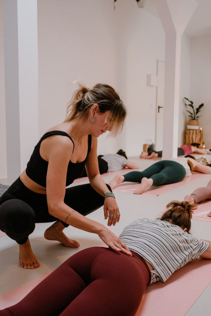 Yogatherapie: Frau in Bauchlage bekommt Adjustiert für mehr Raum im unteren Rücken